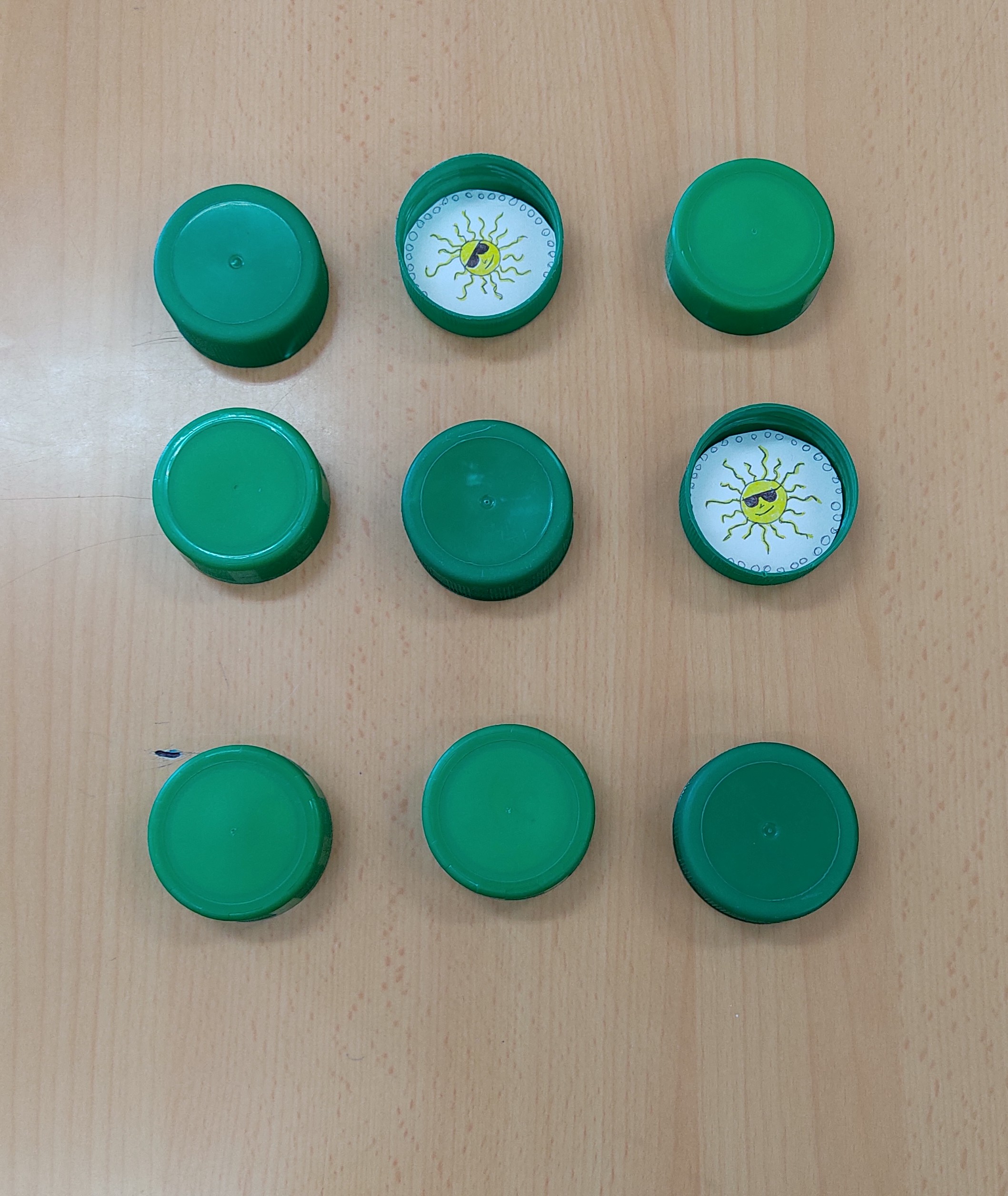 Vista superior del tablero del Juego de Parejas mostrando tapones boca abajo y boca arriba con símbolos de sumas y restas